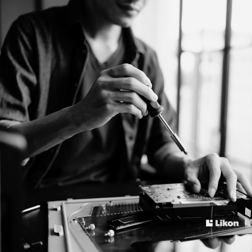 Technik pracuje przy elektronice, używając śrubokręta do montażu lub serwisowania urządzenia, symbolizując integrację i utrzymanie systemów technicznych.