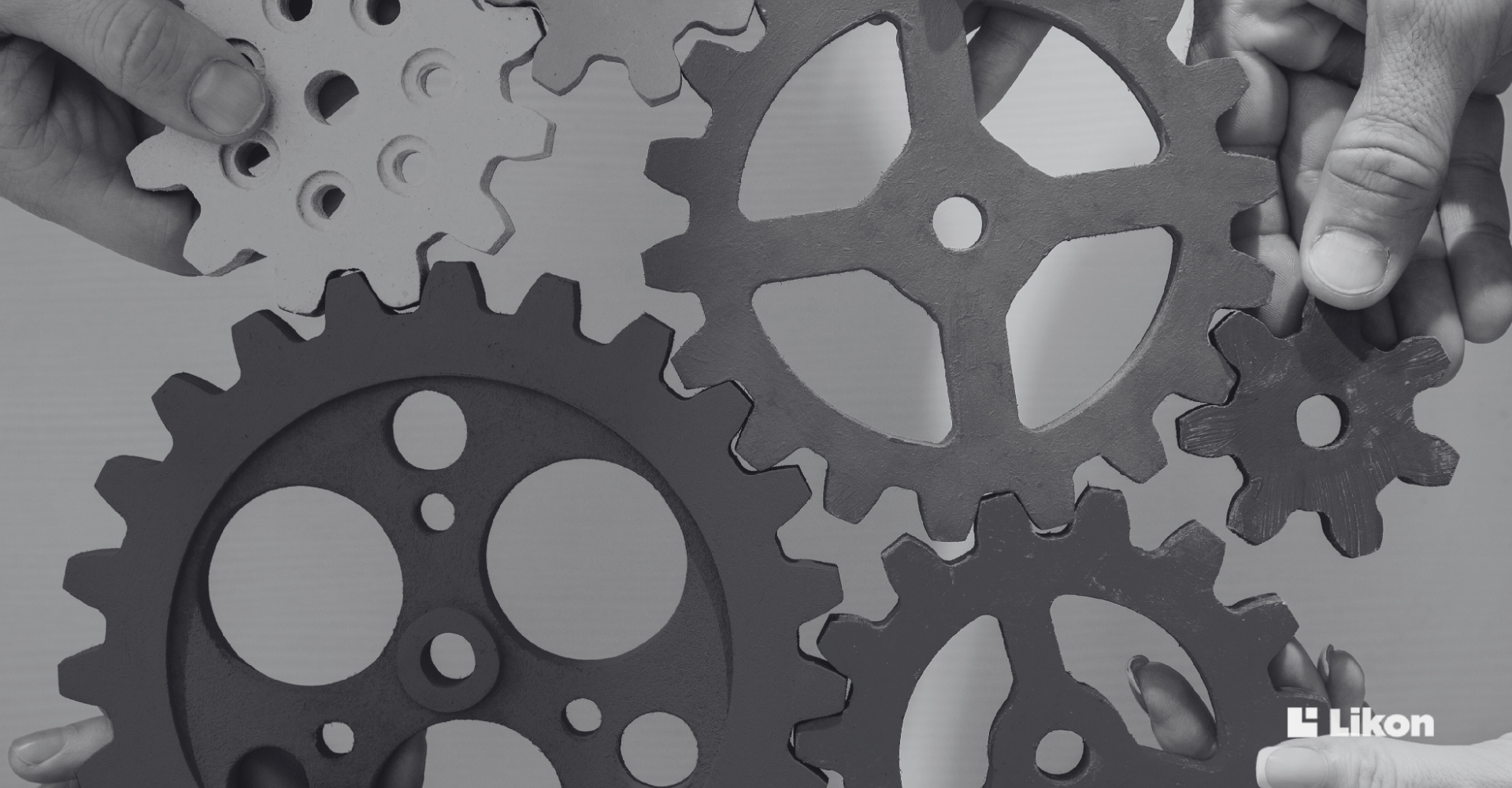 Dłonie układają kilka kół zębatych, symbolizujących integrację systemów i współpracę elementów infrastruktury dla większego bezpieczeństwa firmy.